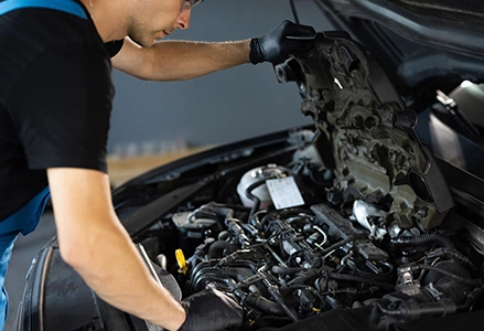 A mechanic using a grinder to repair a car, creating sparks.