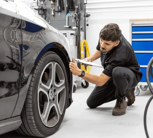 Network Auto Body technician inspecting a vehicle with front body panels removed during professional collision repair and structural assessment.