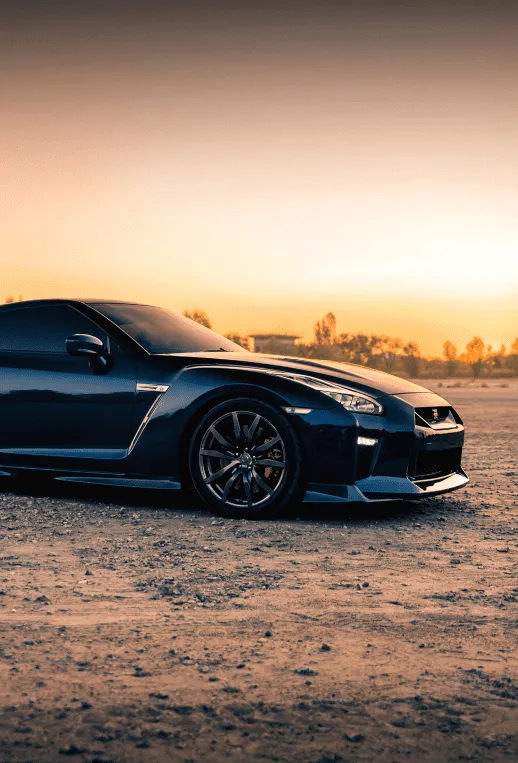 Black sports car parked at sunset with a polished exterior finish, representing precision auto body repair and refinishing services.