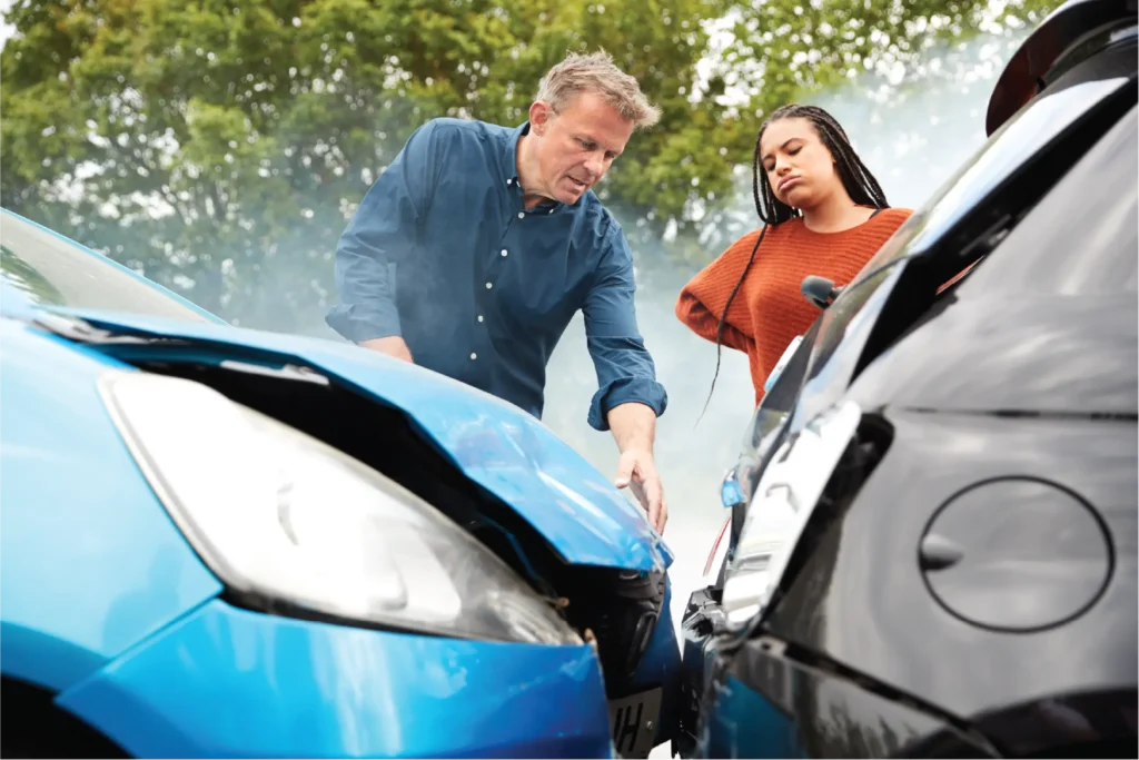 A man and woman inspect their cars after a fender bender.