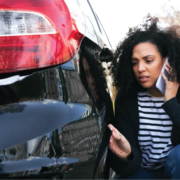 A woman inspects her rear bumper after a minor accident.